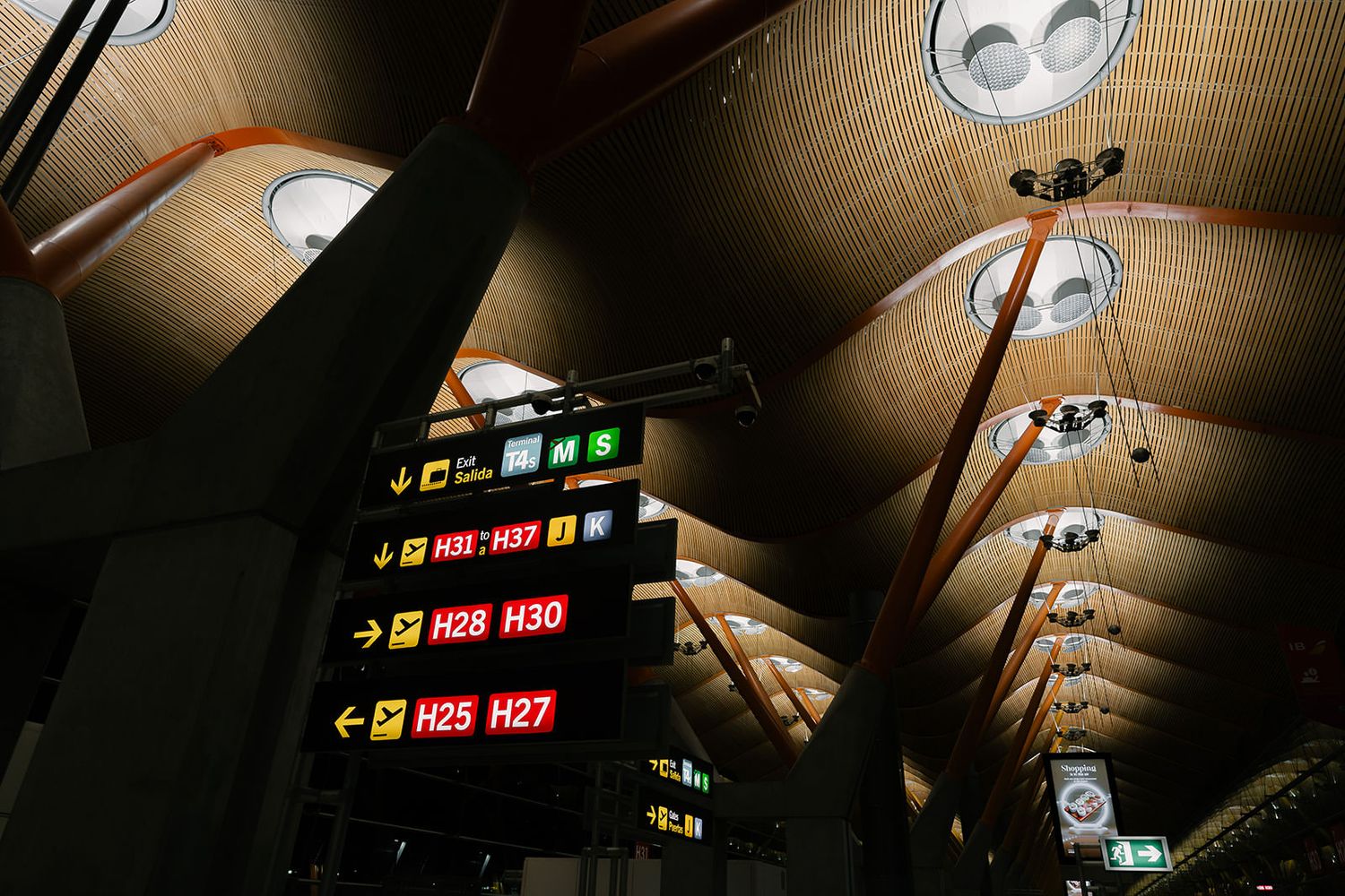 Underground metro station ceiling with illuminated signs and modern lighting fixtures.