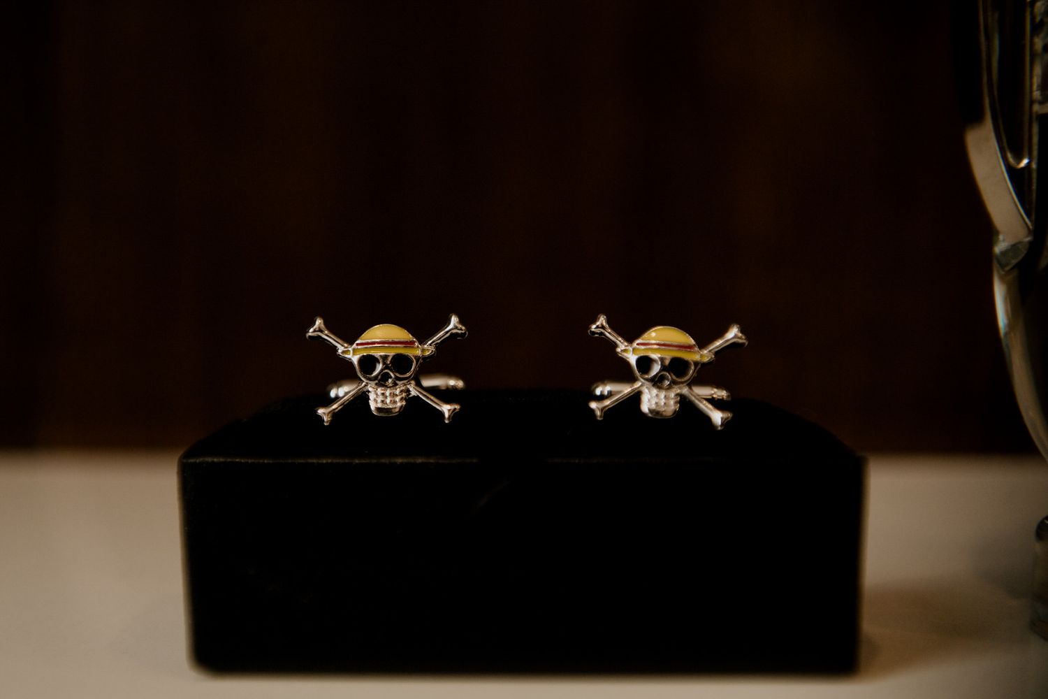 Gold and silver skull crossbones cufflinks displayed on a black jewelry box.