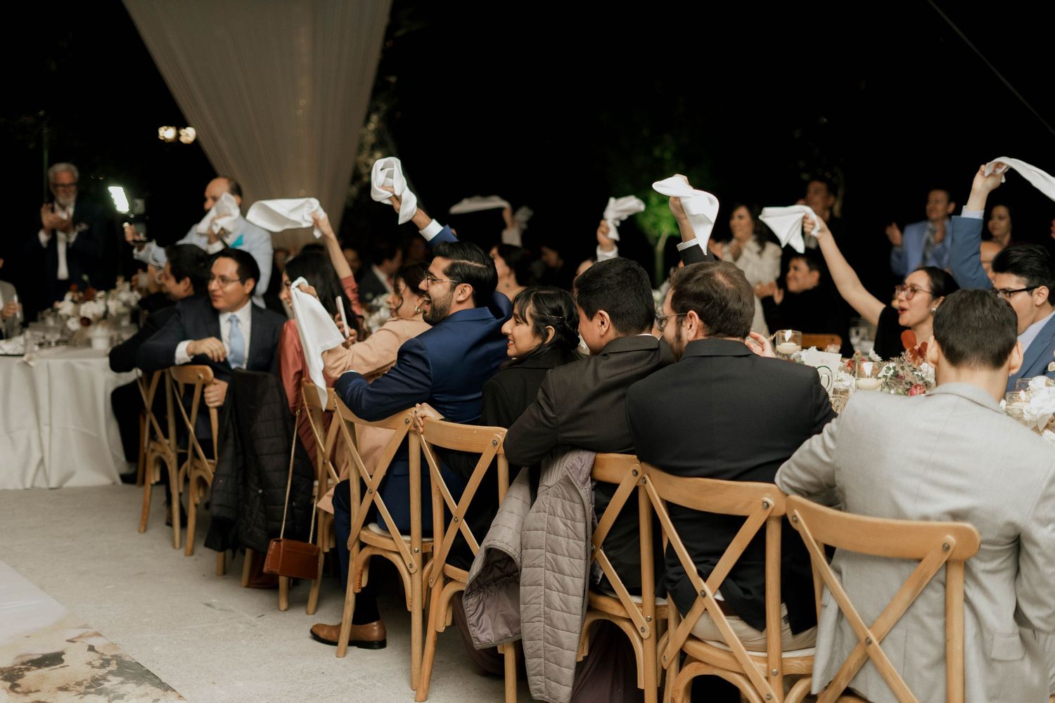 Wedding reception venue with rustic wooden chairs and elegant white draping on the ceiling.