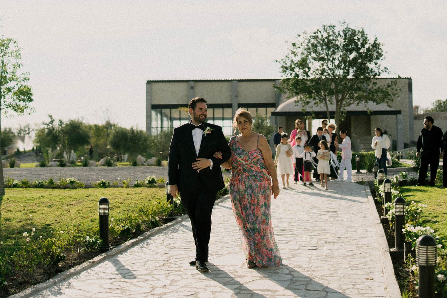 Wedding party walking along a stone path with mountains visible in the distance.