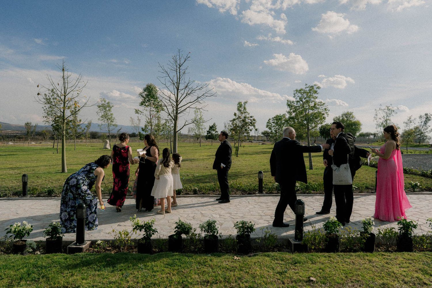 A line of people standing together outdoors against a blue sky and grassy landscape.