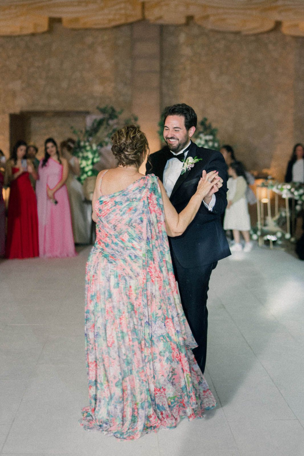 Dancing couple in formal attire spinning on reception floor as guests look on.