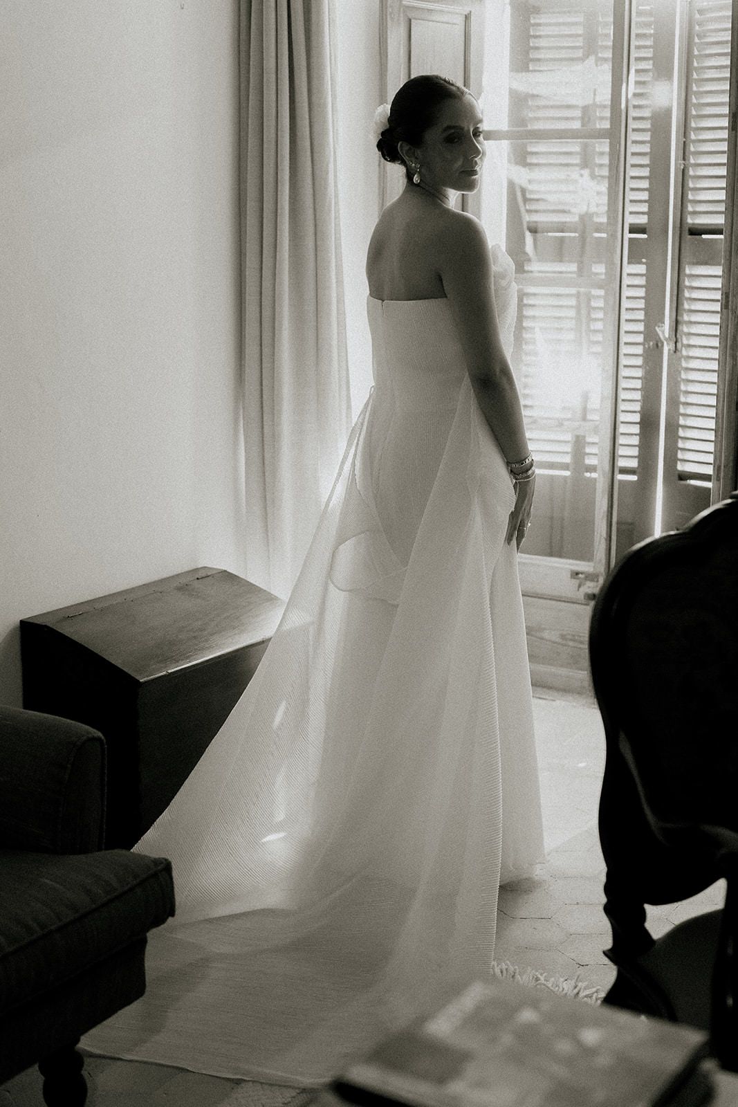 Artistic black and white series showing flowing white wedding dress movement against window light.