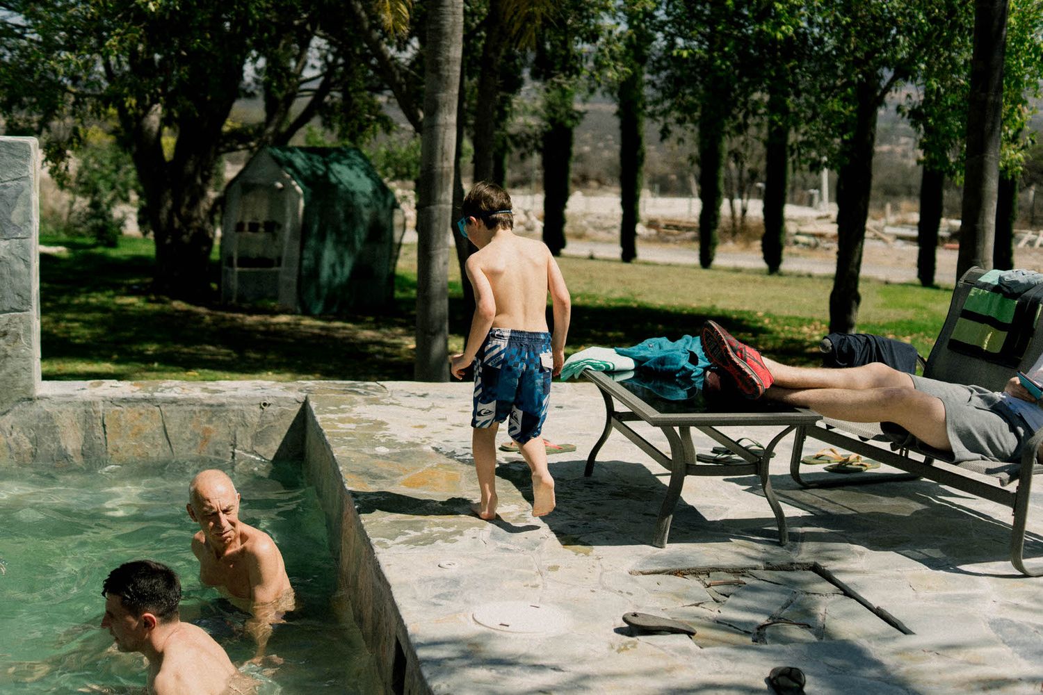 People enjoying a swimming pool area with lounge chairs at a resort.