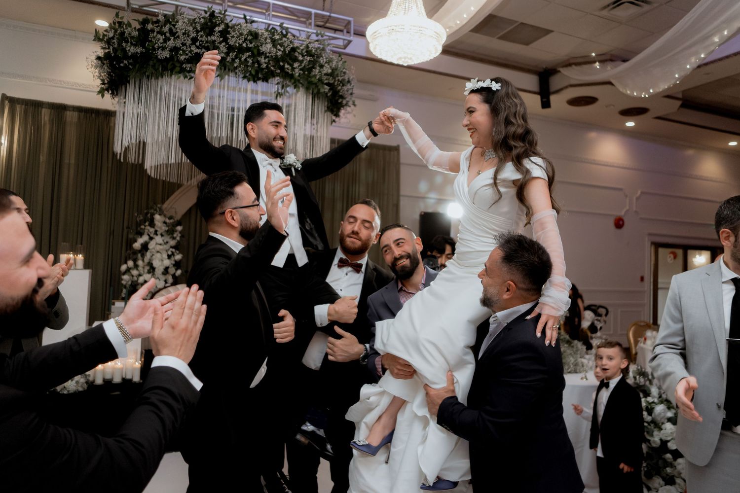 Wedding celebration with dancing and festivities in a decorated indoor venue.