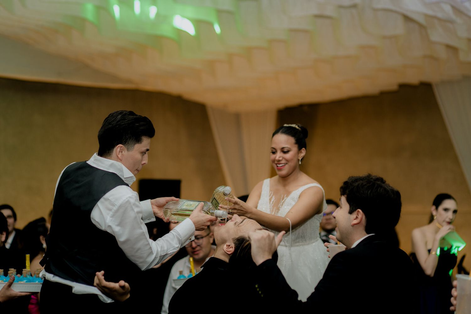 Bride and groom sharing a joyful moment with guests during a wedding reception celebration indoors.