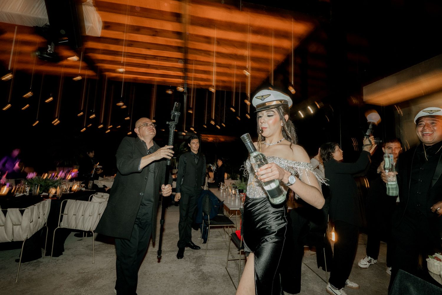 Wedding guests dancing and celebrating on a dimly lit dance floor at an evening reception.