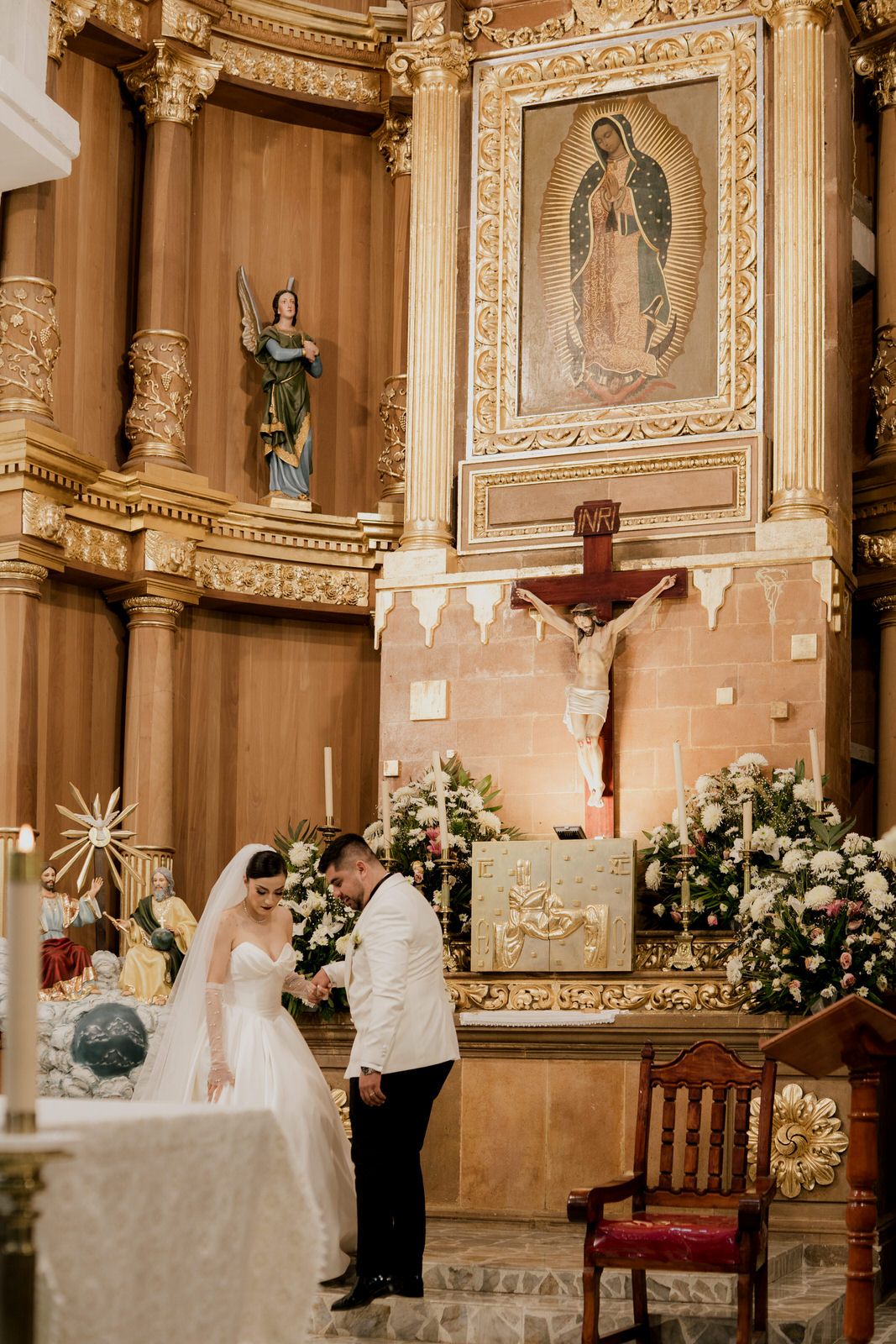 Wedding ceremony in a grand cathedral with ornate gold details and religious artwork.