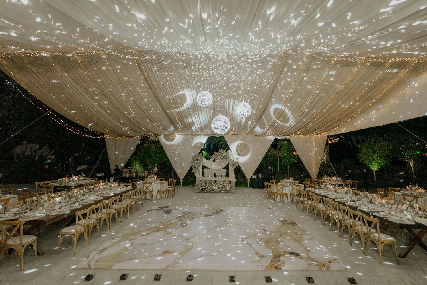 Wedding tent ceiling decorated with twinkling string lights and white fabric creating a romantic canopy.