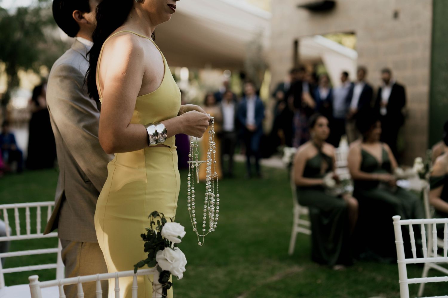 Wedding reception setup with white chairs and decorative elements on grass.