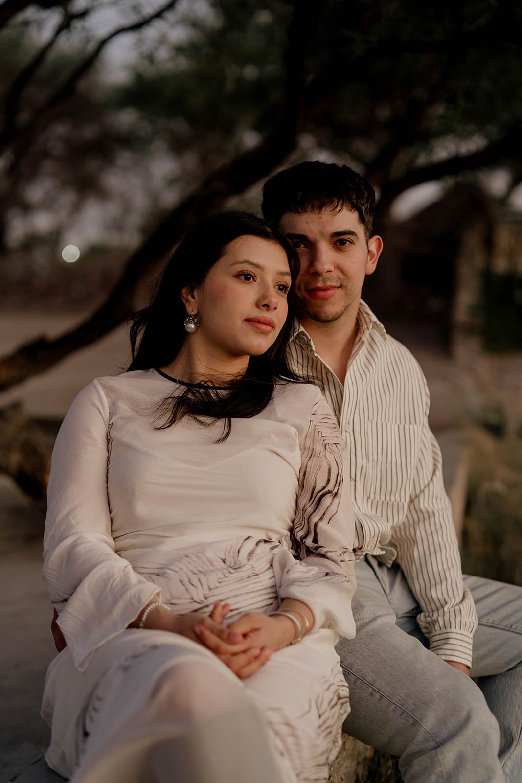 A couple shares an intimate moment together while sitting outdoors at dusk.