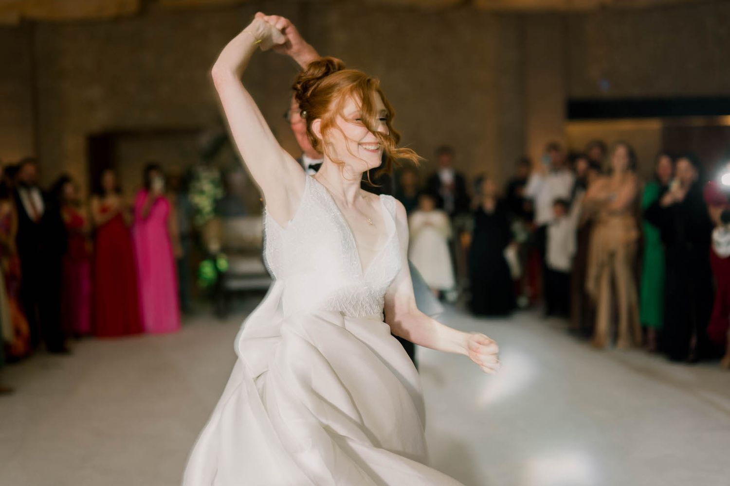 A couple performs their first dance at a wedding reception surrounded by guests.