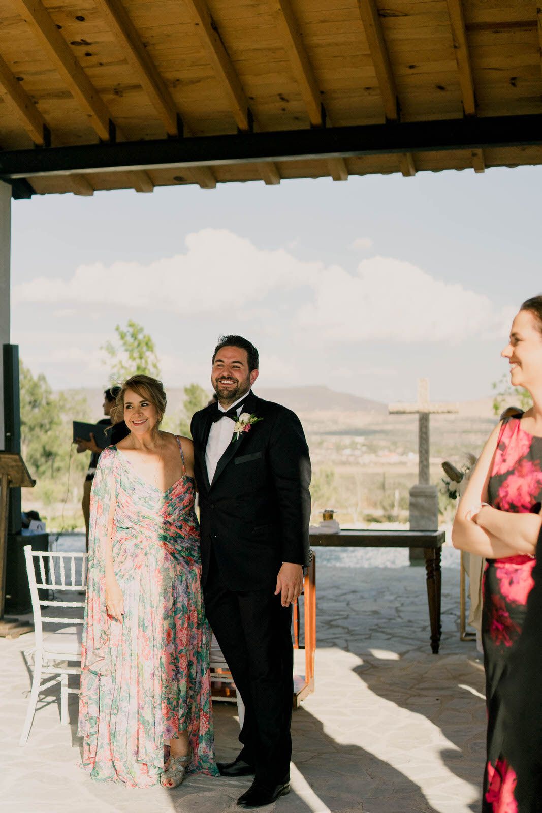 Wedding celebration under rustic wooden pavilion with scenic mountain views.