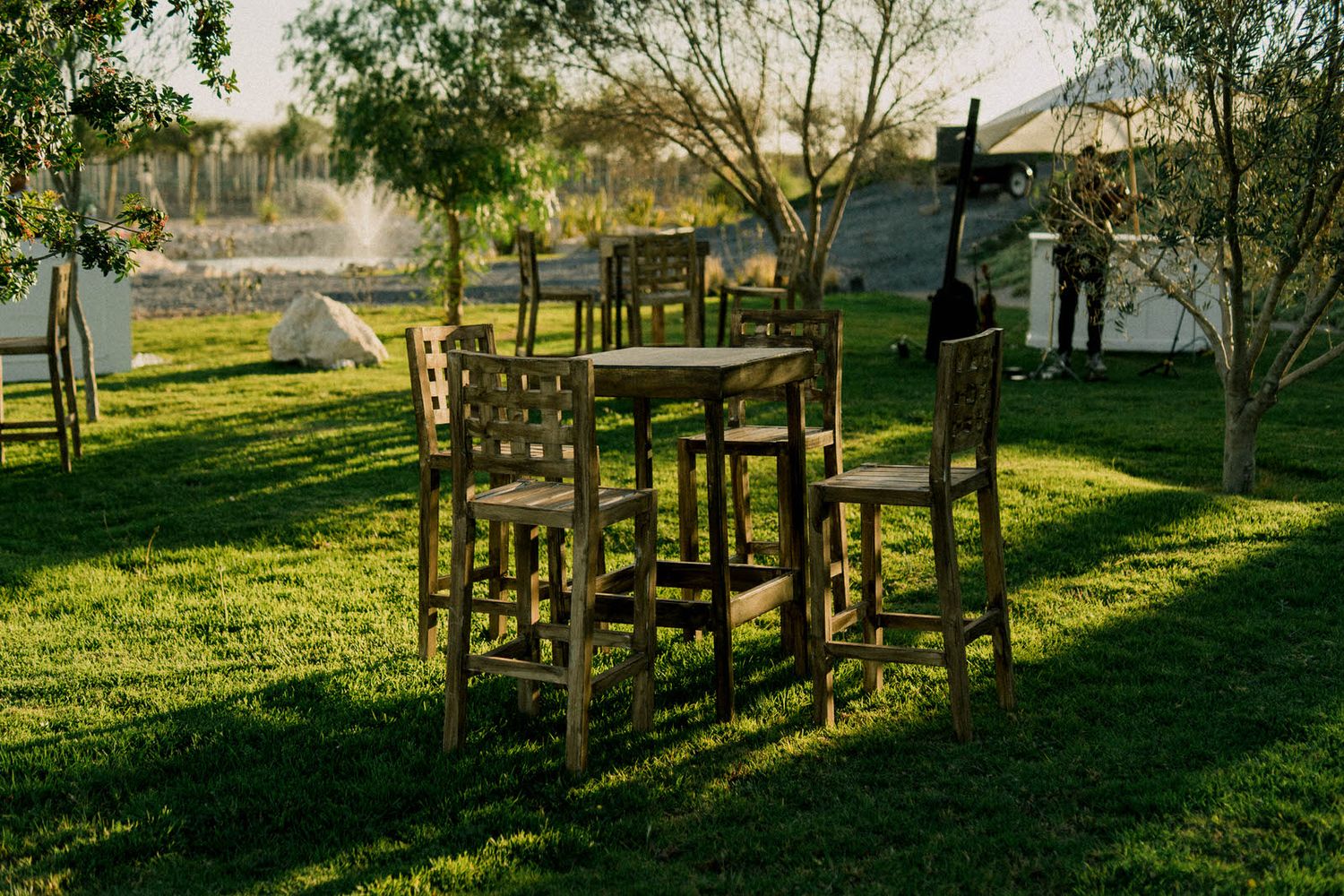 Rustic wooden chairs arranged on green lawn during golden hour.