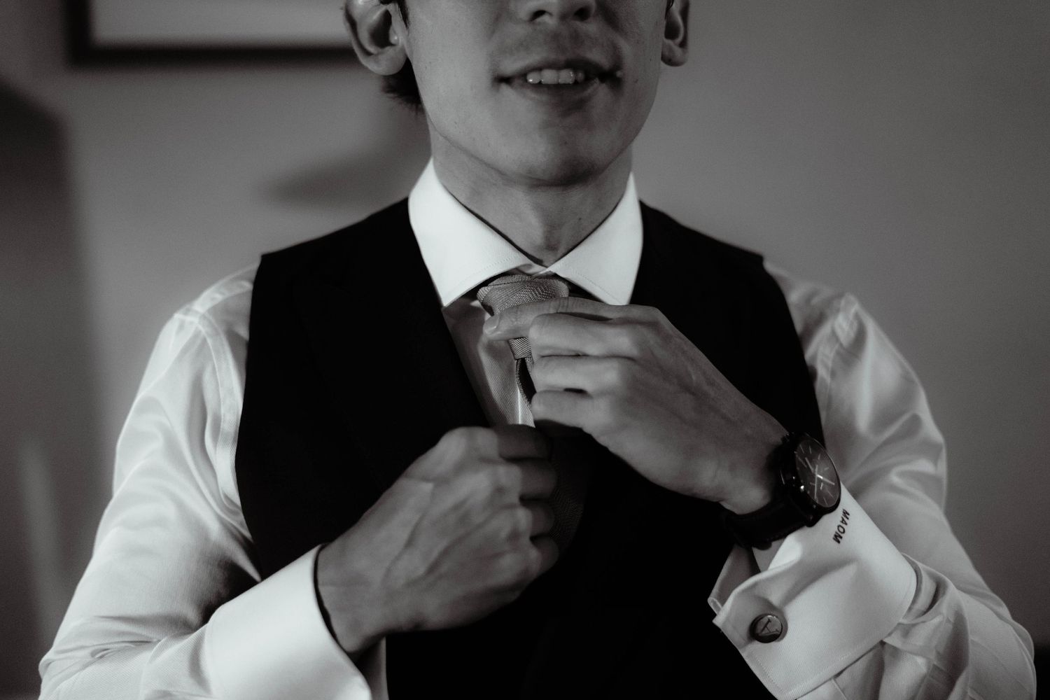 Close-up shots of formal attire adjustments showing black vest and white shirt details.