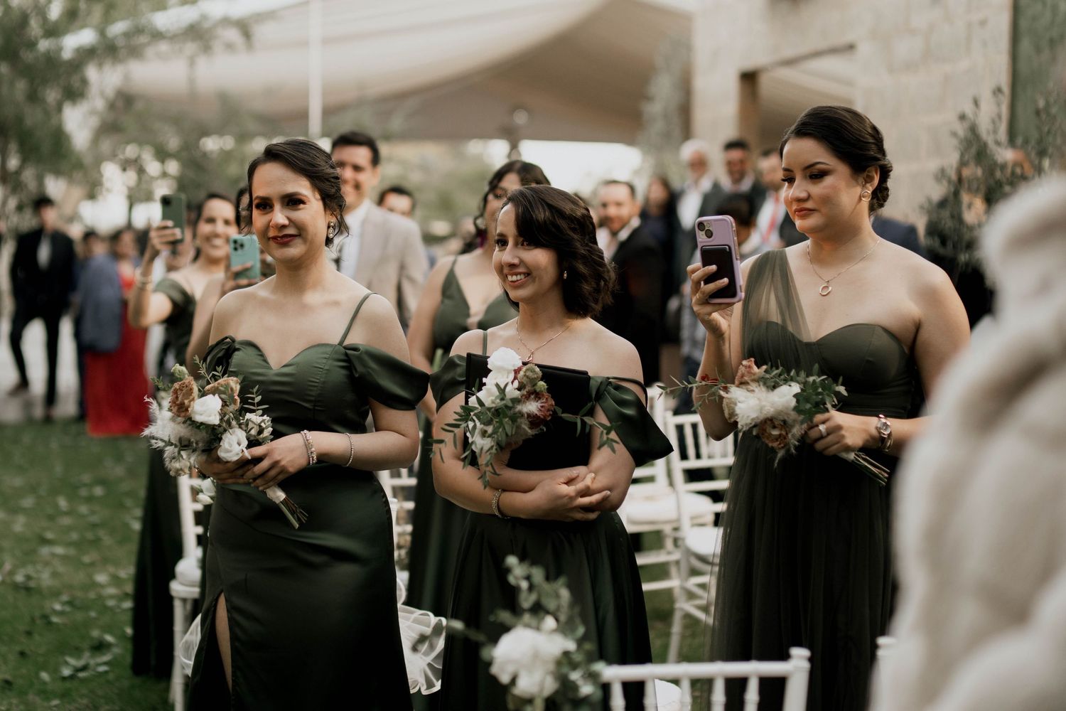 Wedding celebration in a garden setting with formal attire and white chairs.