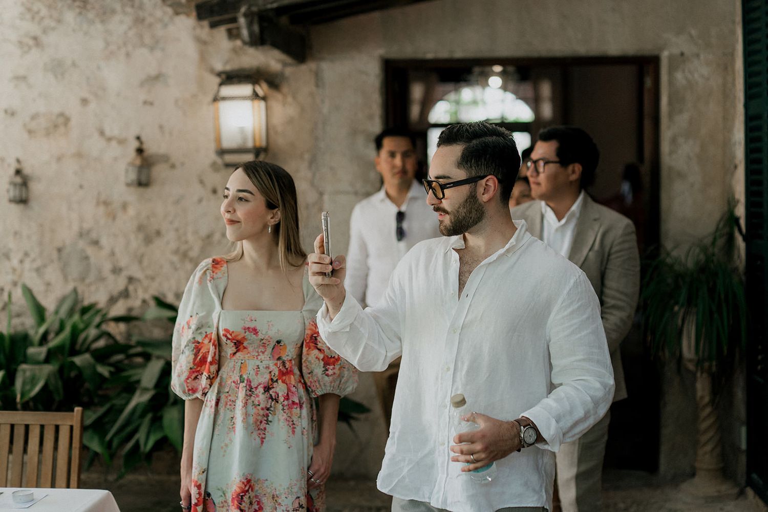 Guests mingling at an outdoor reception with rustic stone walls and natural lighting.