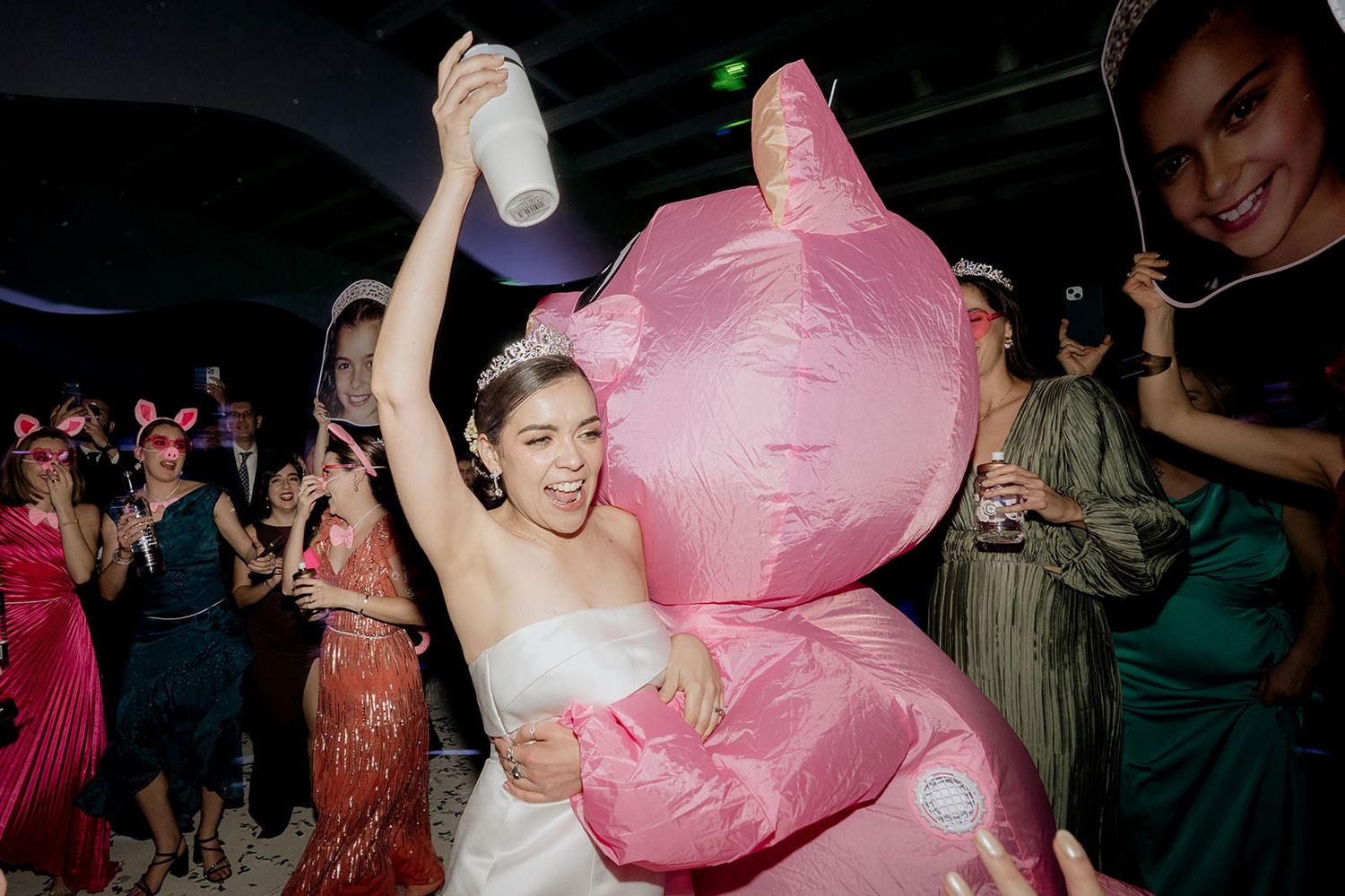 Bride dancing with large pink inflatable bear at fun wedding reception celebration.