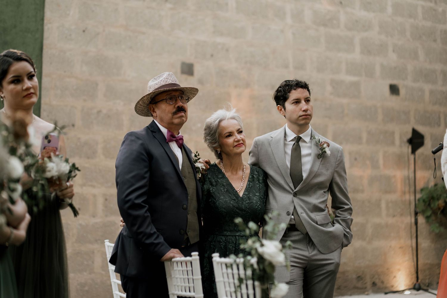 Guests gather for wedding festivities against stone wall background.