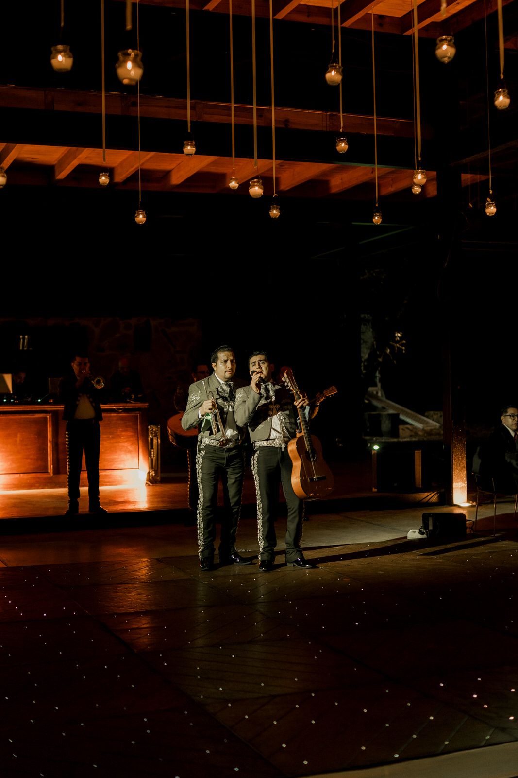Dimly lit wedding reception dance floor with hanging Edison bulbs creating dramatic atmosphere.