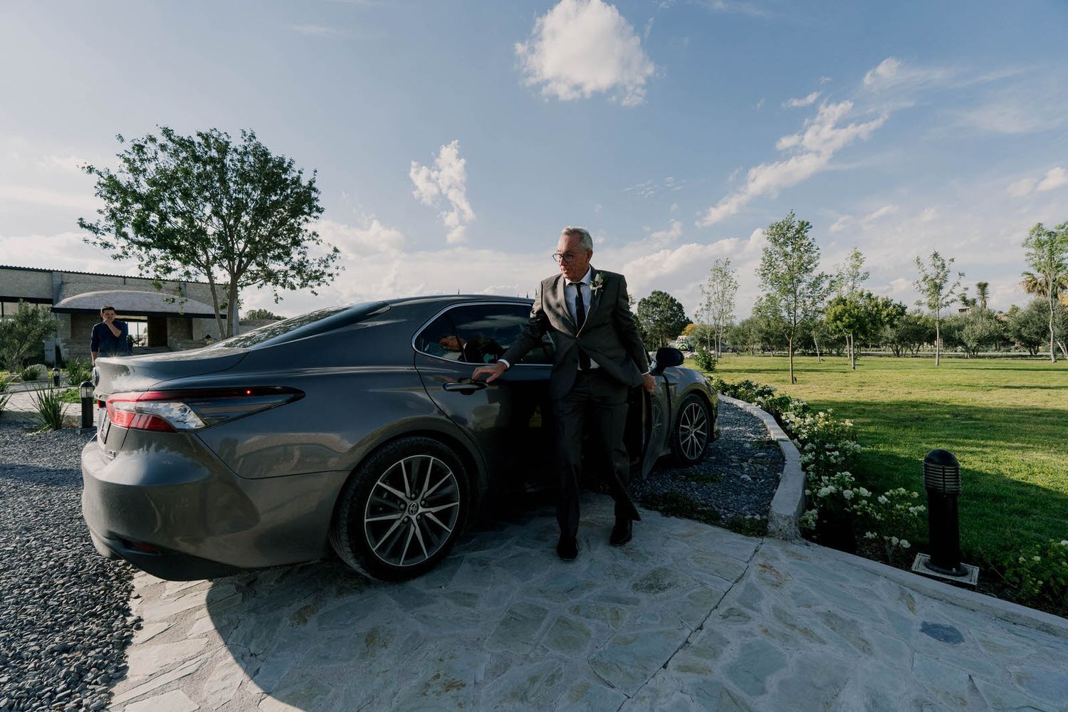 Luxury car parked at outdoor wedding venue with mountains and blue sky in background.