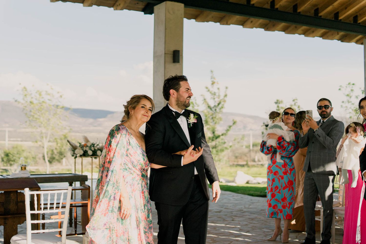 Elegant outdoor wedding ceremony setup with wooden beams and mountain backdrop.