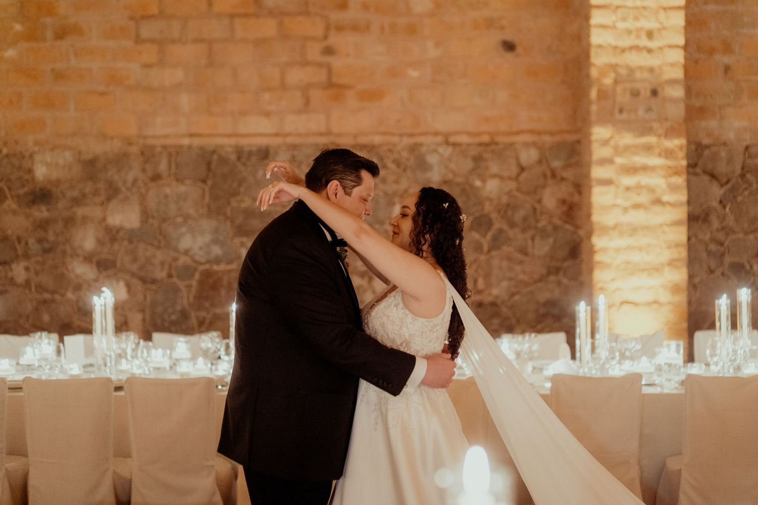 Wedding venue preparation in a historic brick cellar with elegant white table settings.