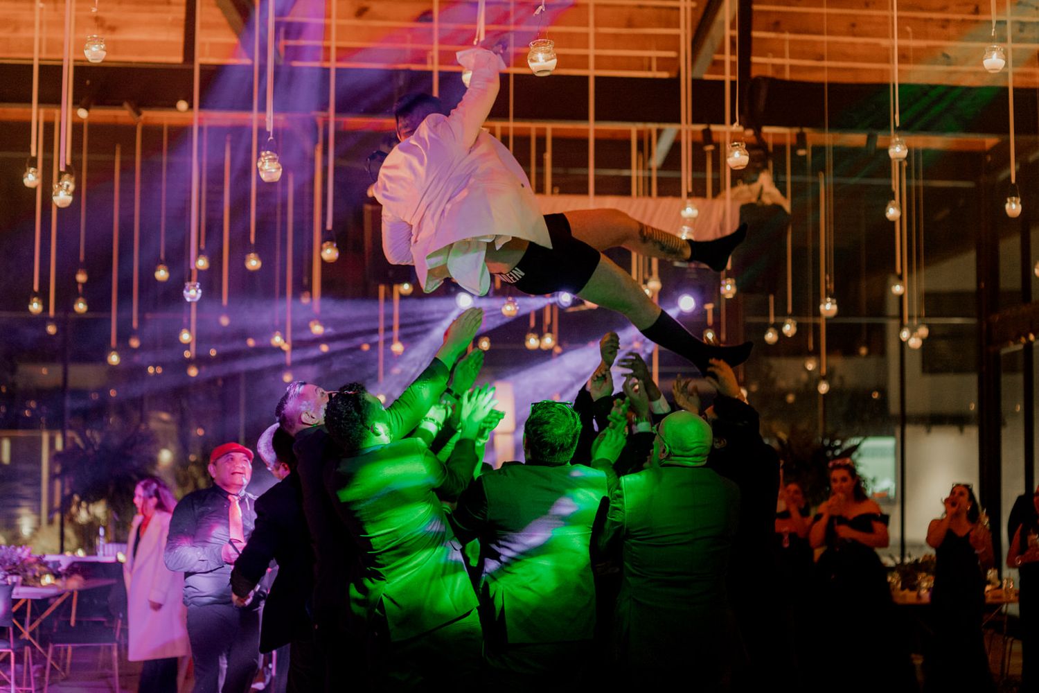 Wedding venue decorated with purple and green lighting effects and hanging string lights creating an ambient atmosphere.