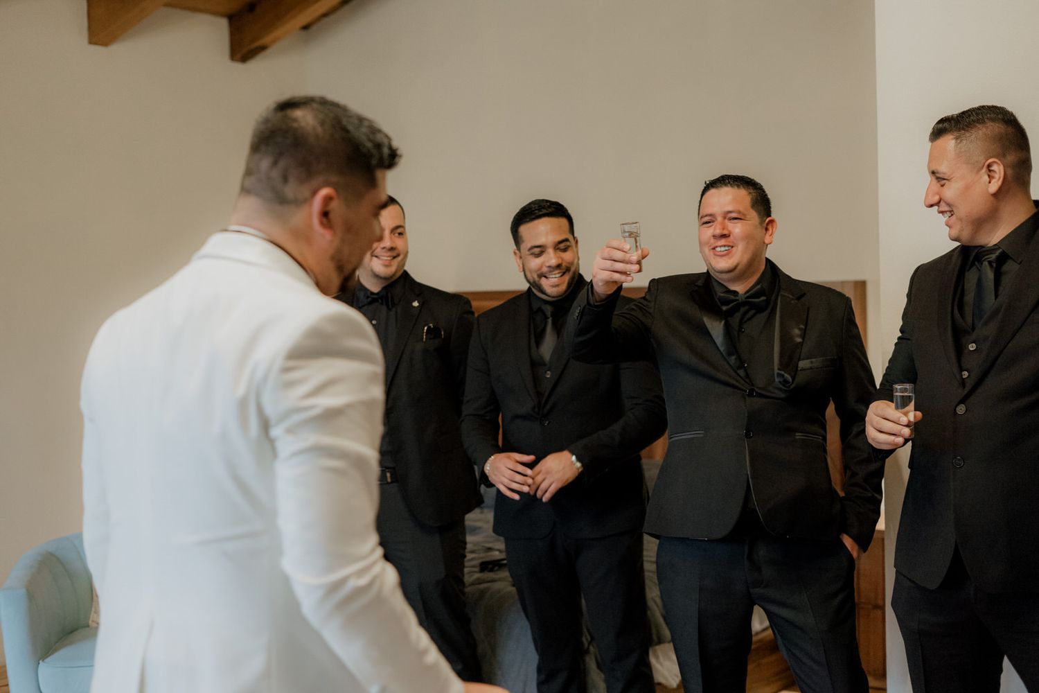 Wedding party members gather in casual conversation before the ceremony begins.