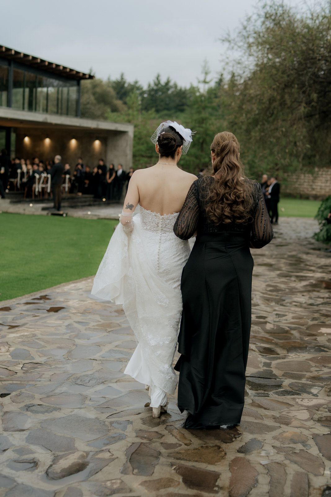Couple walks together on stone pathway during outdoor wedding ceremony.