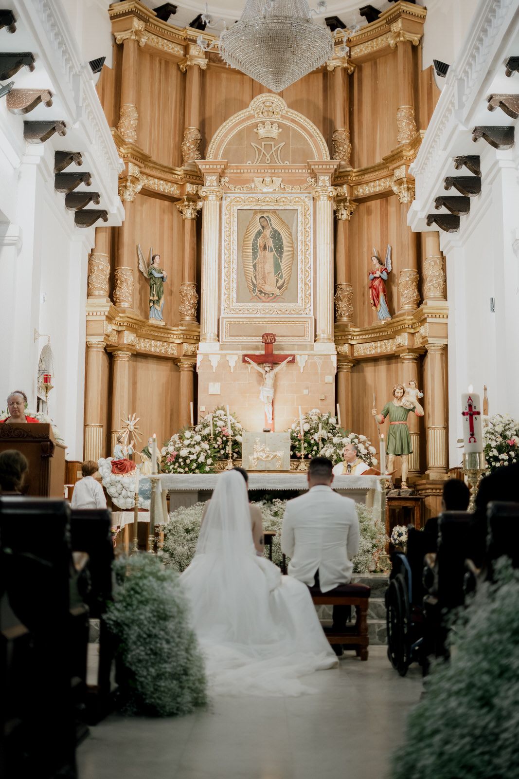 A grand Catholic church altar with ornate gold details and religious imagery during a wedding ceremony.