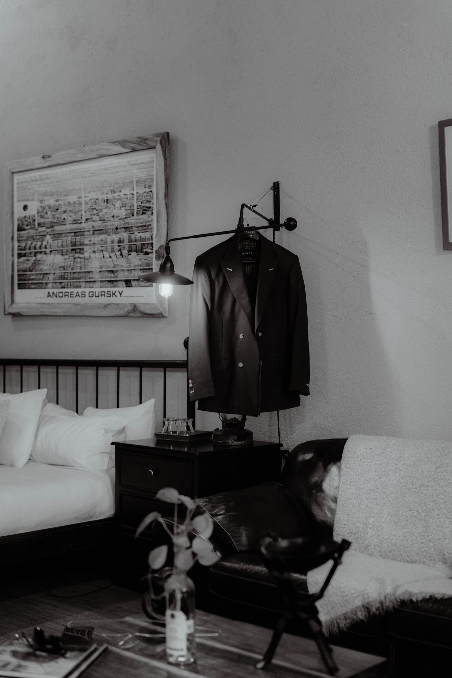 Black and white interior scene with jacket hanging and framed artwork in a minimalist bedroom.