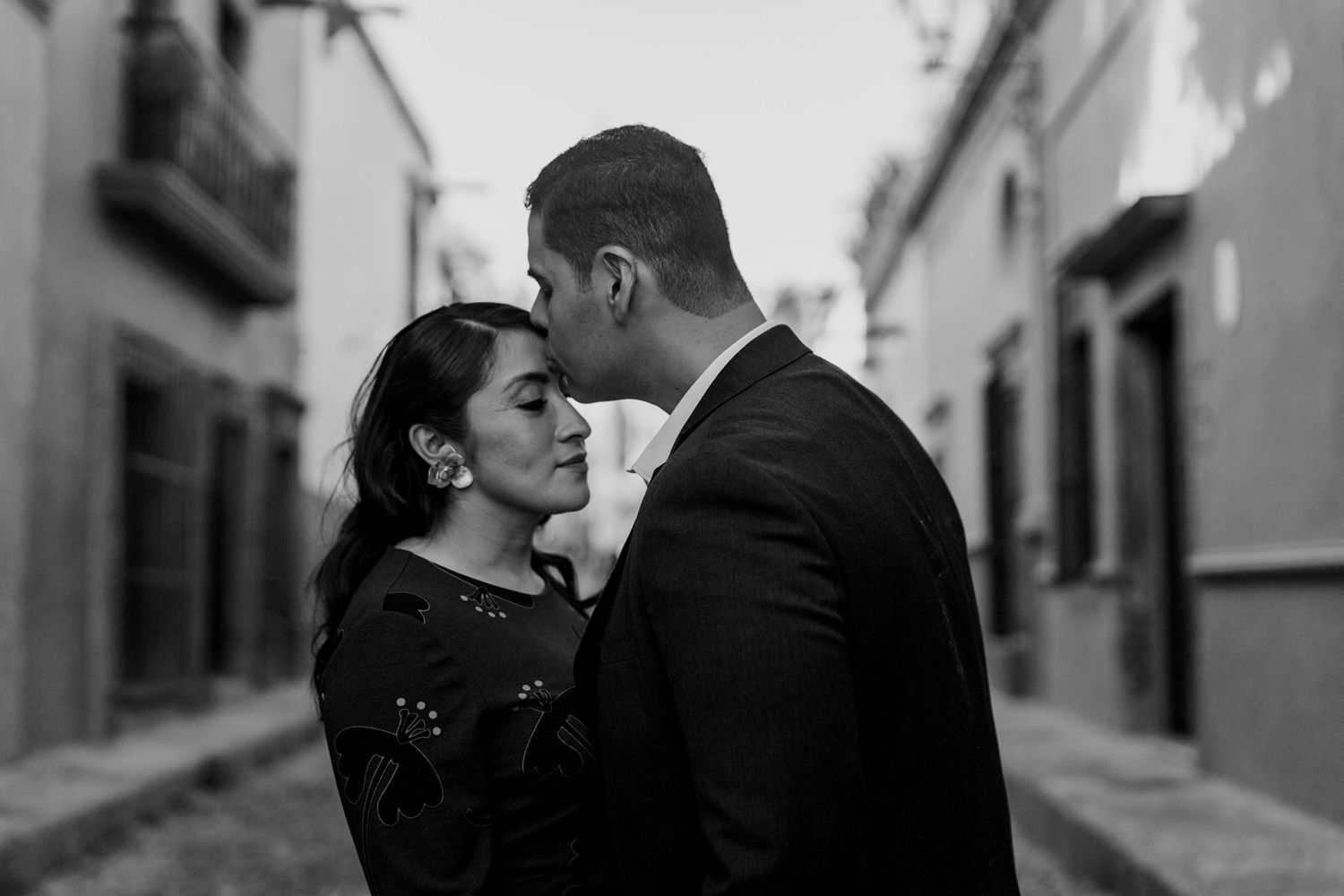 An intimate black and white portrait in a narrow colonial alleyway.