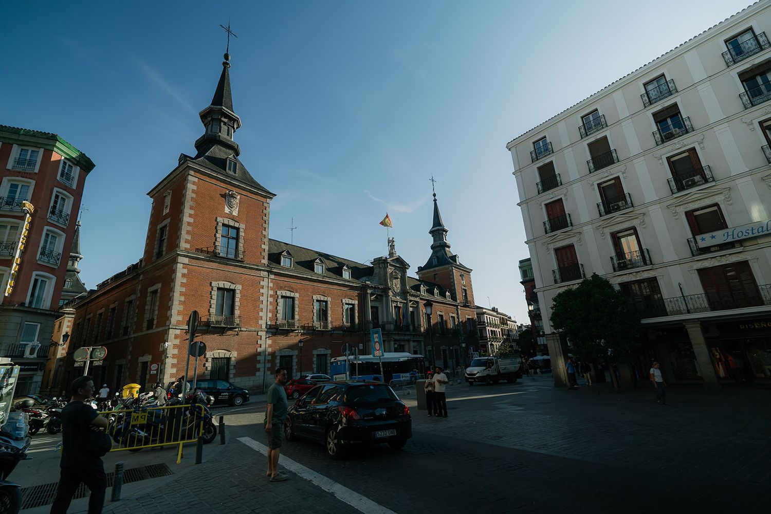 Historic town square with church spires and traditional European architecture under blue sky.