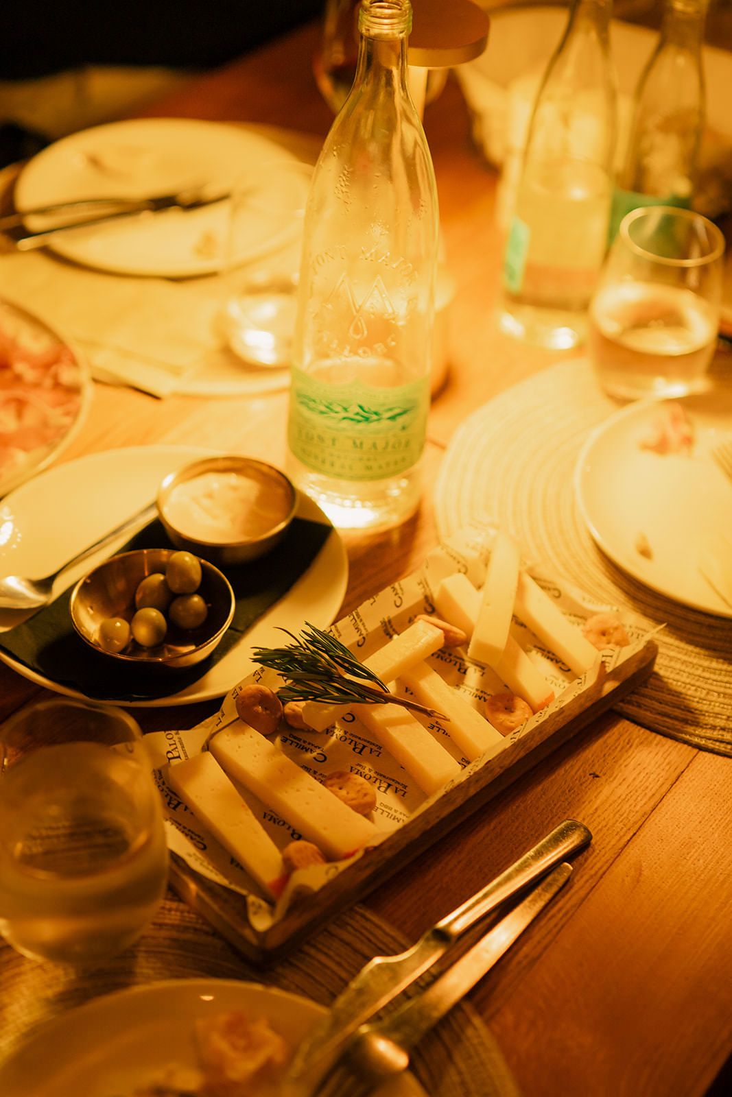 Warm-lit dining table setting with plates and wine glasses in a restaurant's intimate atmosphere.