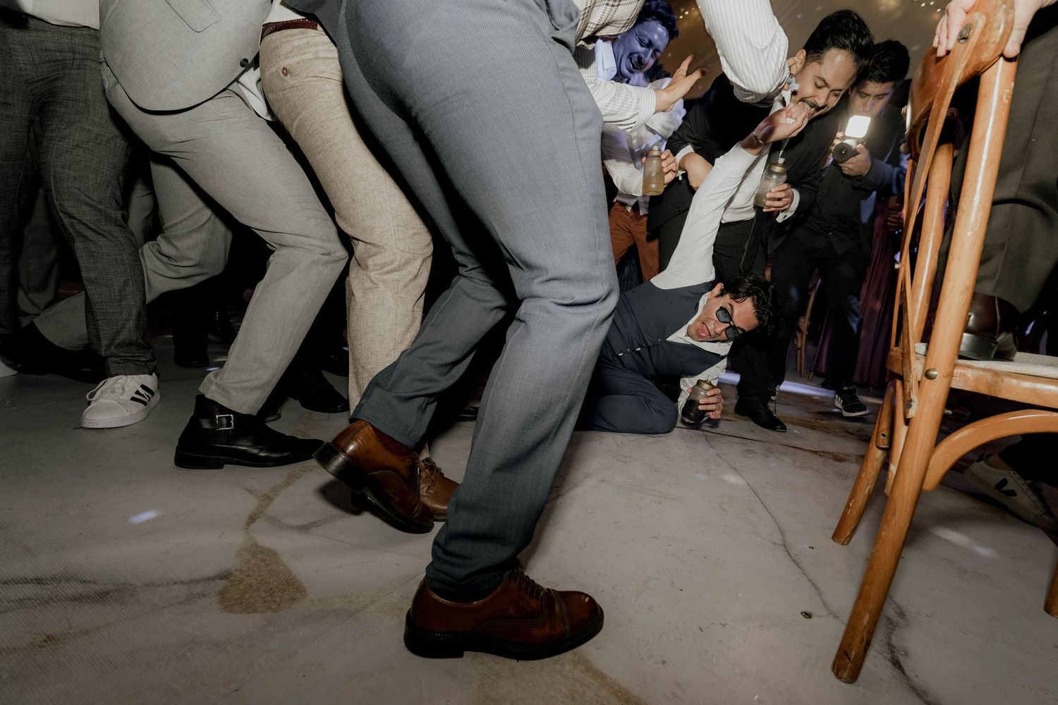 Wedding guests' feet and legs visible on dance floor during lively reception celebration.
