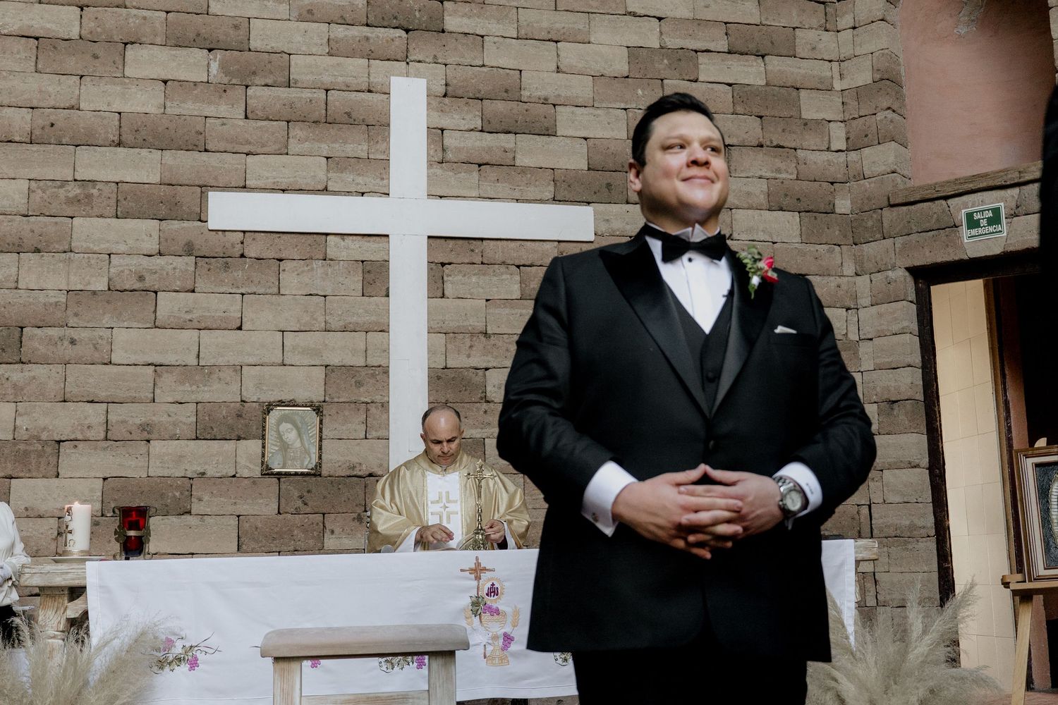 Church ceremony setup with stone walls and cross backdrop.