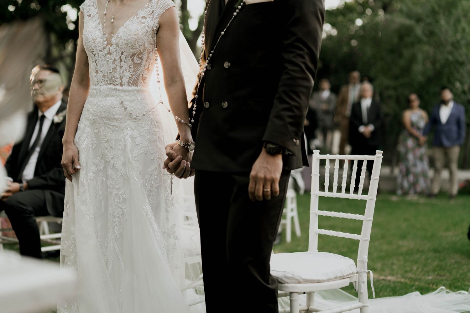 Romantic wedding ceremony moment captured in an outdoor garden setting with white chairs.