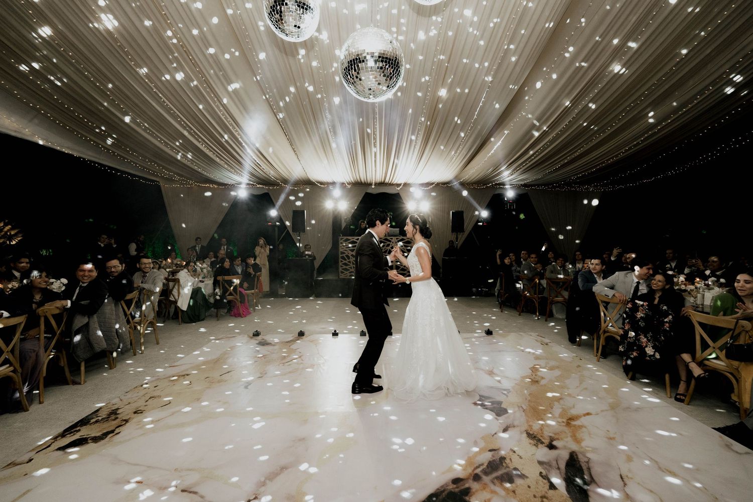 Wedding reception dance floor with disco ball and string lights creating a magical atmosphere.