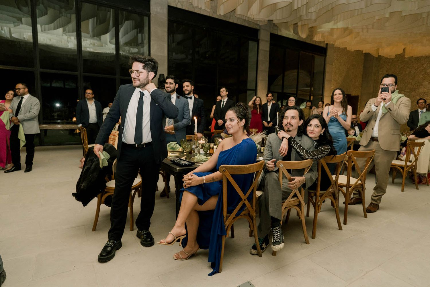 Wedding celebration in rustic stone venue with guests seated at round tables.