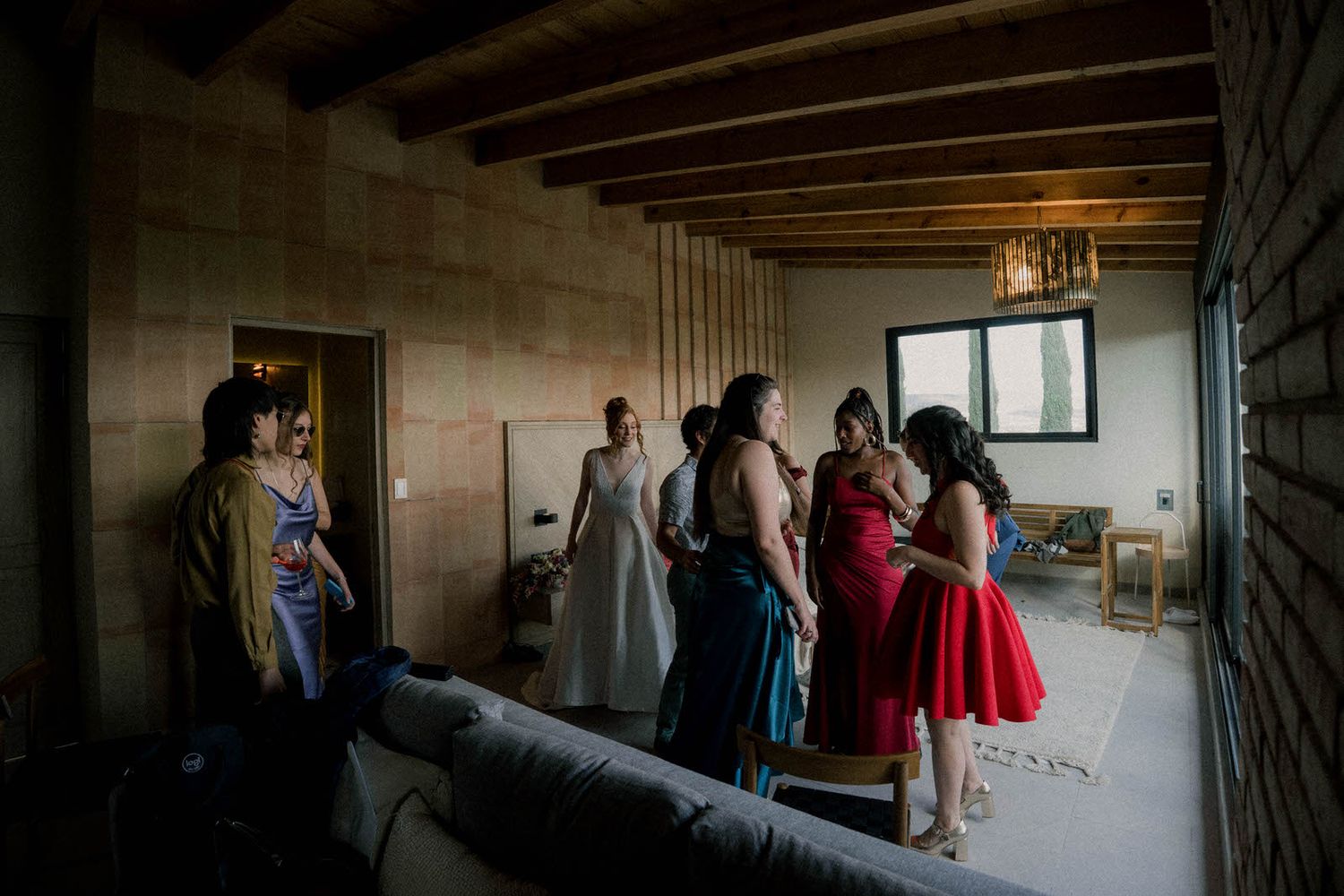 Wedding party members gather in a rustic venue with exposed wooden beams.