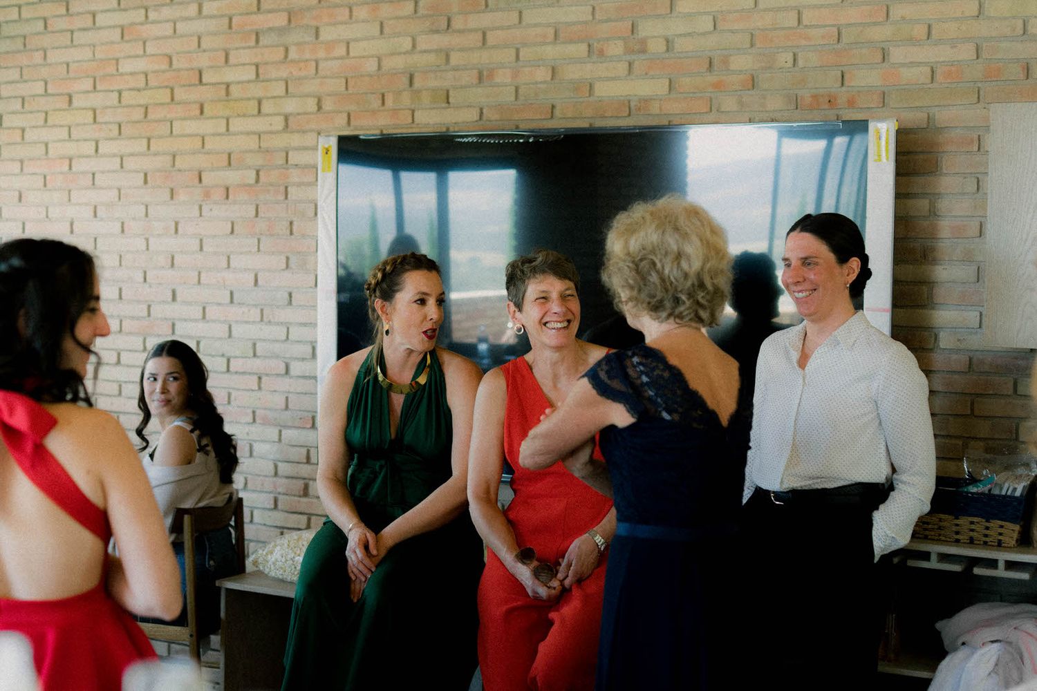 Group gathering in a brick-walled room with people mingling and socializing.