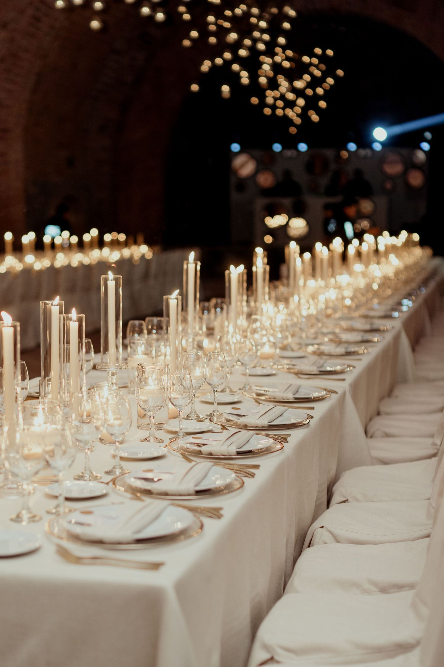 Elegant wedding table setting with white linens and tall candles in a formal dining arrangement.