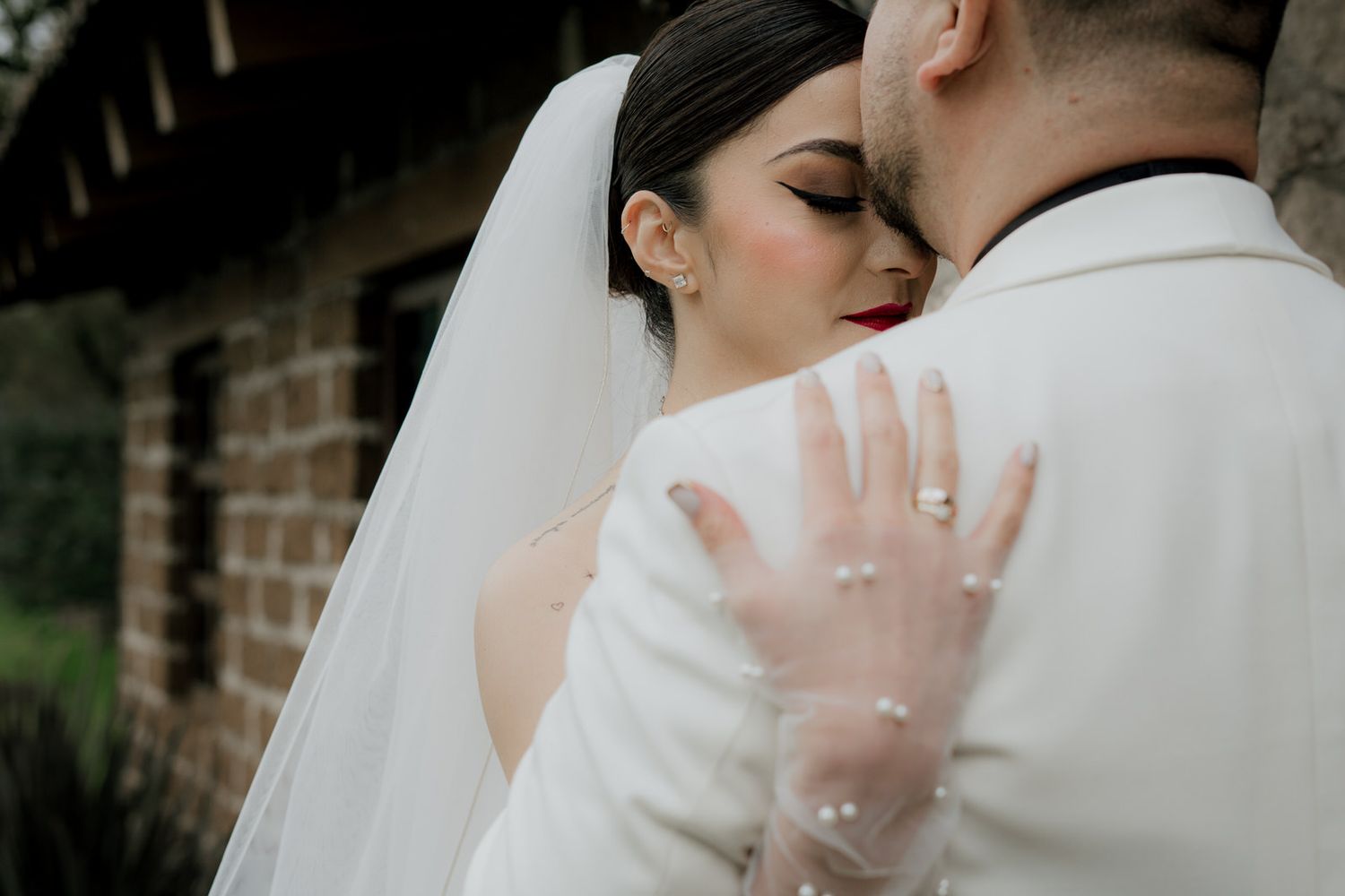Romantic close-up of couple embracing, with bride's hand showing wedding ring.