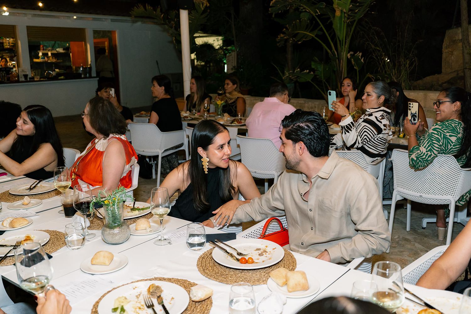 A group of people enjoying dinner together at a casual restaurant with white tablecloths.