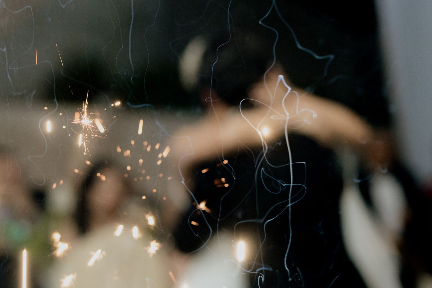 Romantic wedding first dance captured through sparkling bokeh lights and sparklers.