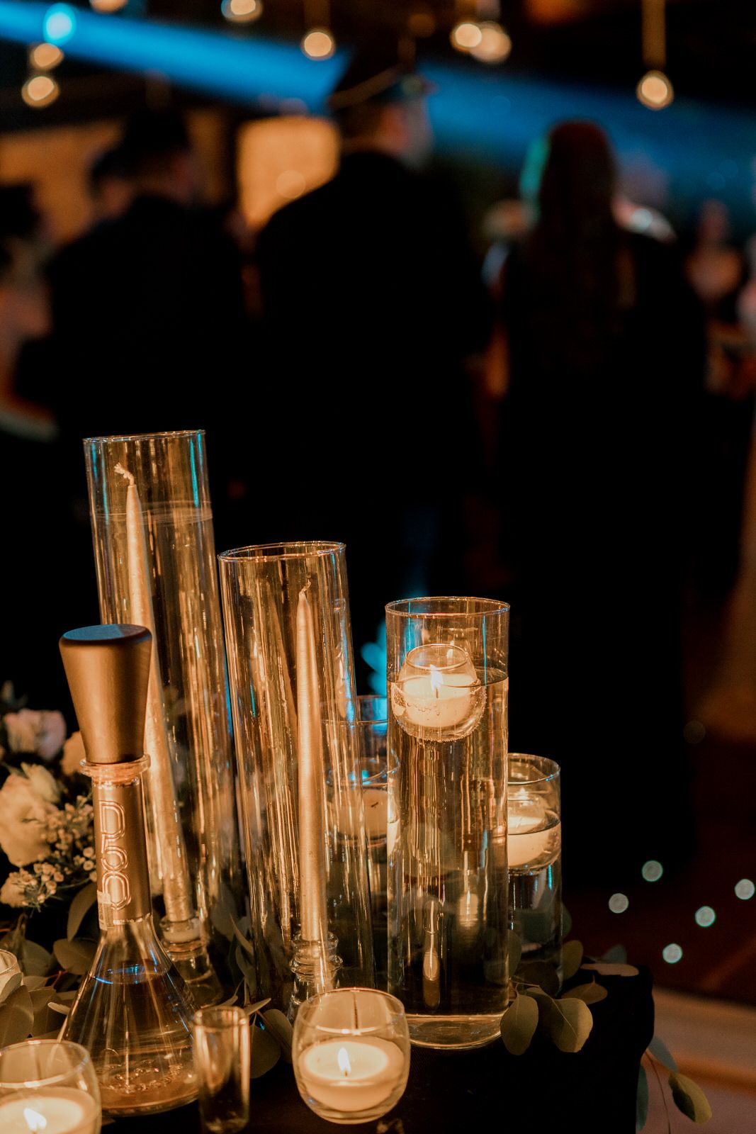 Glowing glass candle holders and vases creating ambient lighting at evening event.