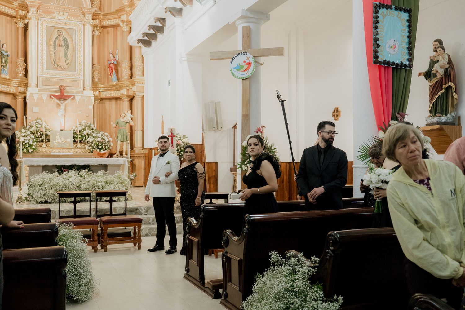 Church interior with red drapes and wooden pews decorated for a wedding ceremony.