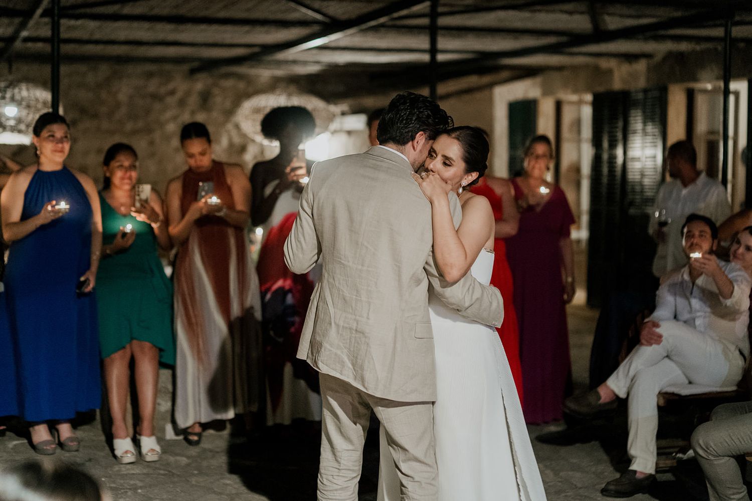 People dancing and mingling at a dimly lit indoor venue with stone walls and ambient lighting.