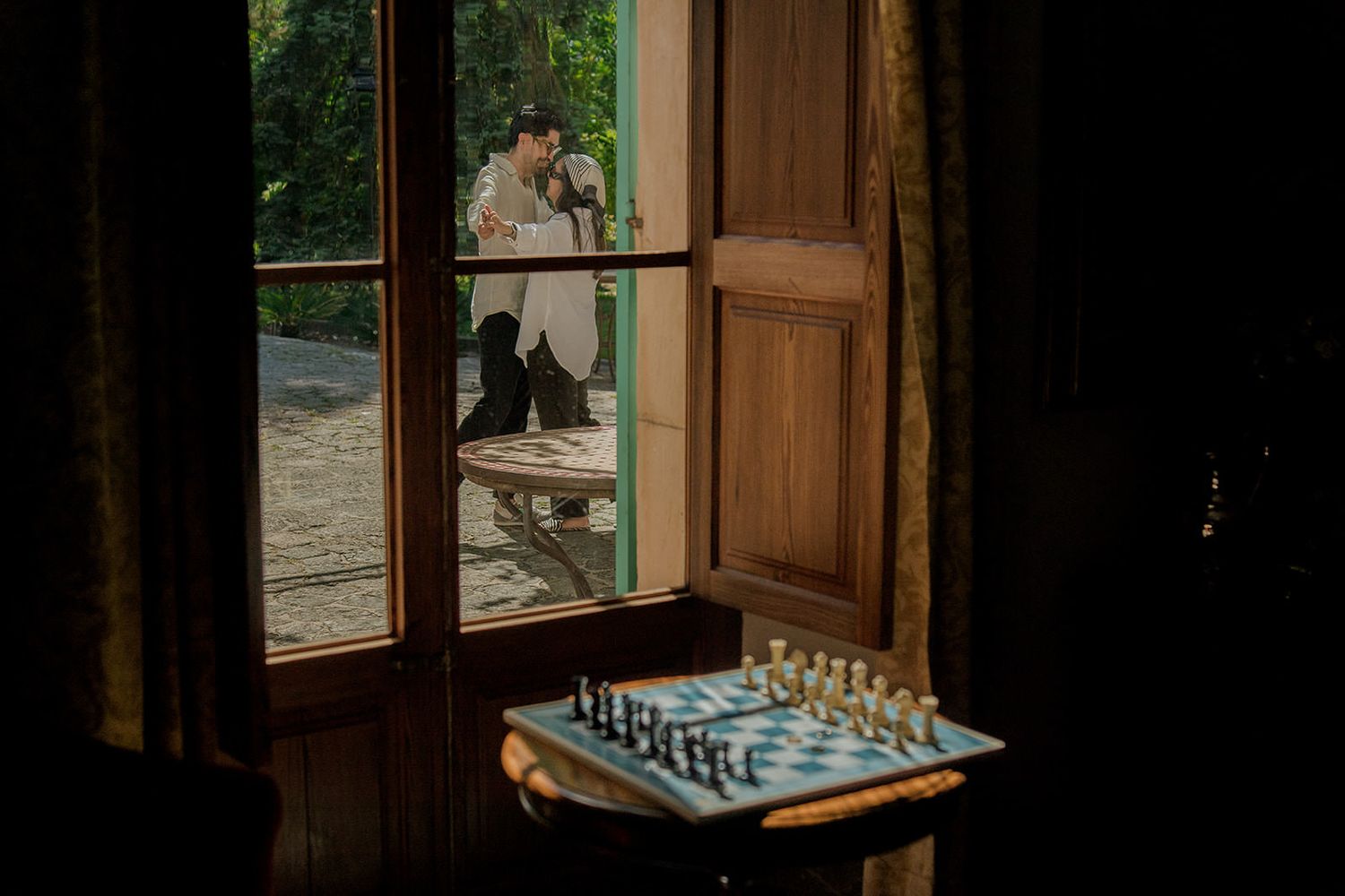 A rustic wooden window sill with a chess board set up for play in a dimly lit room.